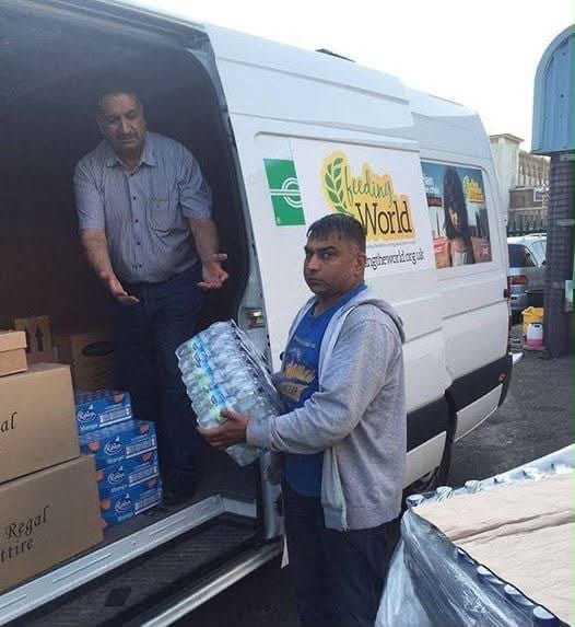 Volunteers unloading water and food supplies from the Feeding The World van
